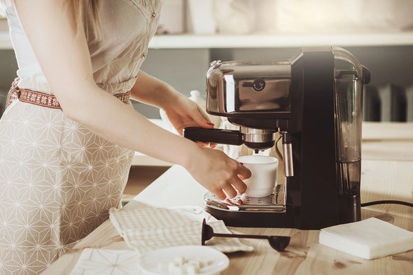 Evde Barista olan bir kadın ve önünde bir espresso makinesi